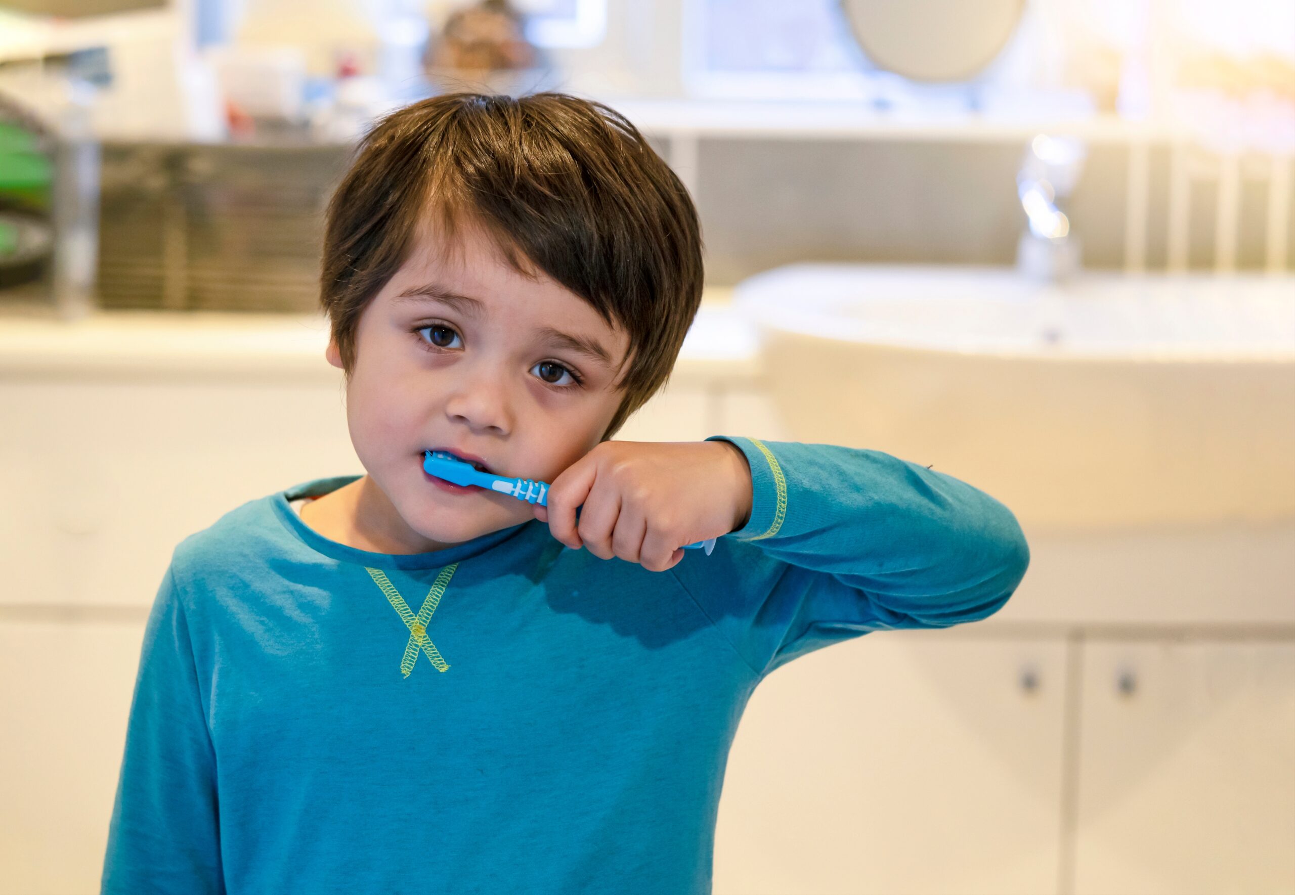 Niño pequeño cepillándose los dientes con ayuda de su madre, como parte de una rutina dental saludable.