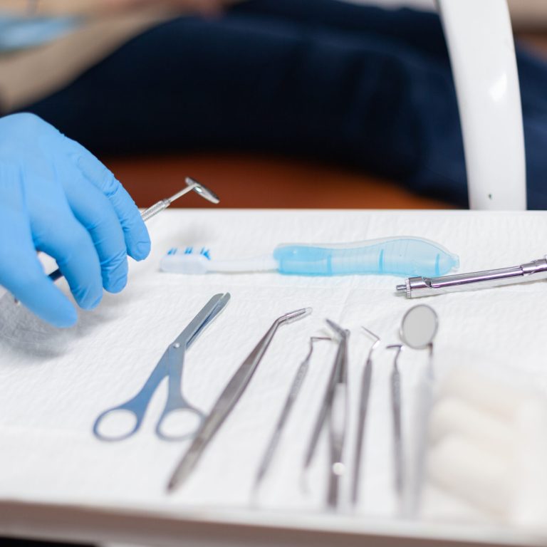 Close up stomatolog taking ustensils for dental intervention of senior woman. Elderly patient during medical examination with dentist in stomatology office with orange equipment.
